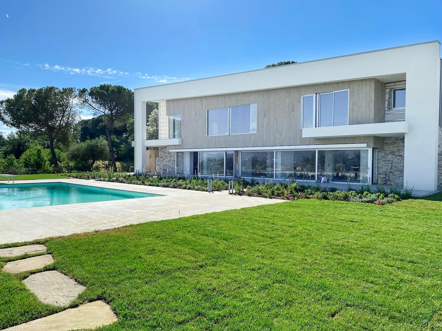 Casa moderna con piscina, circondata da un ampio giardino.